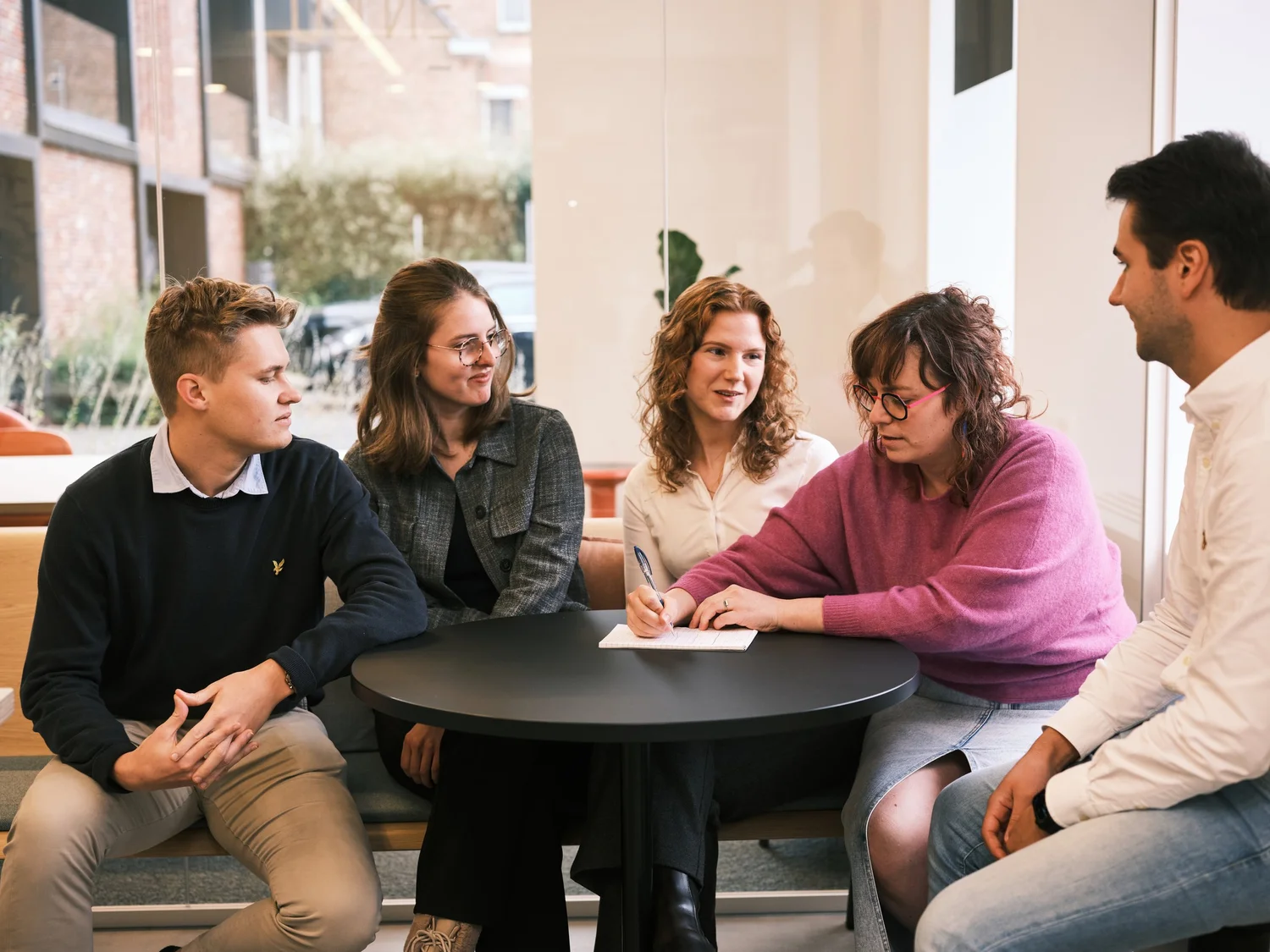 Het Plainsight-team werkt samen rond een laptop in een lichte vergaderruimte
